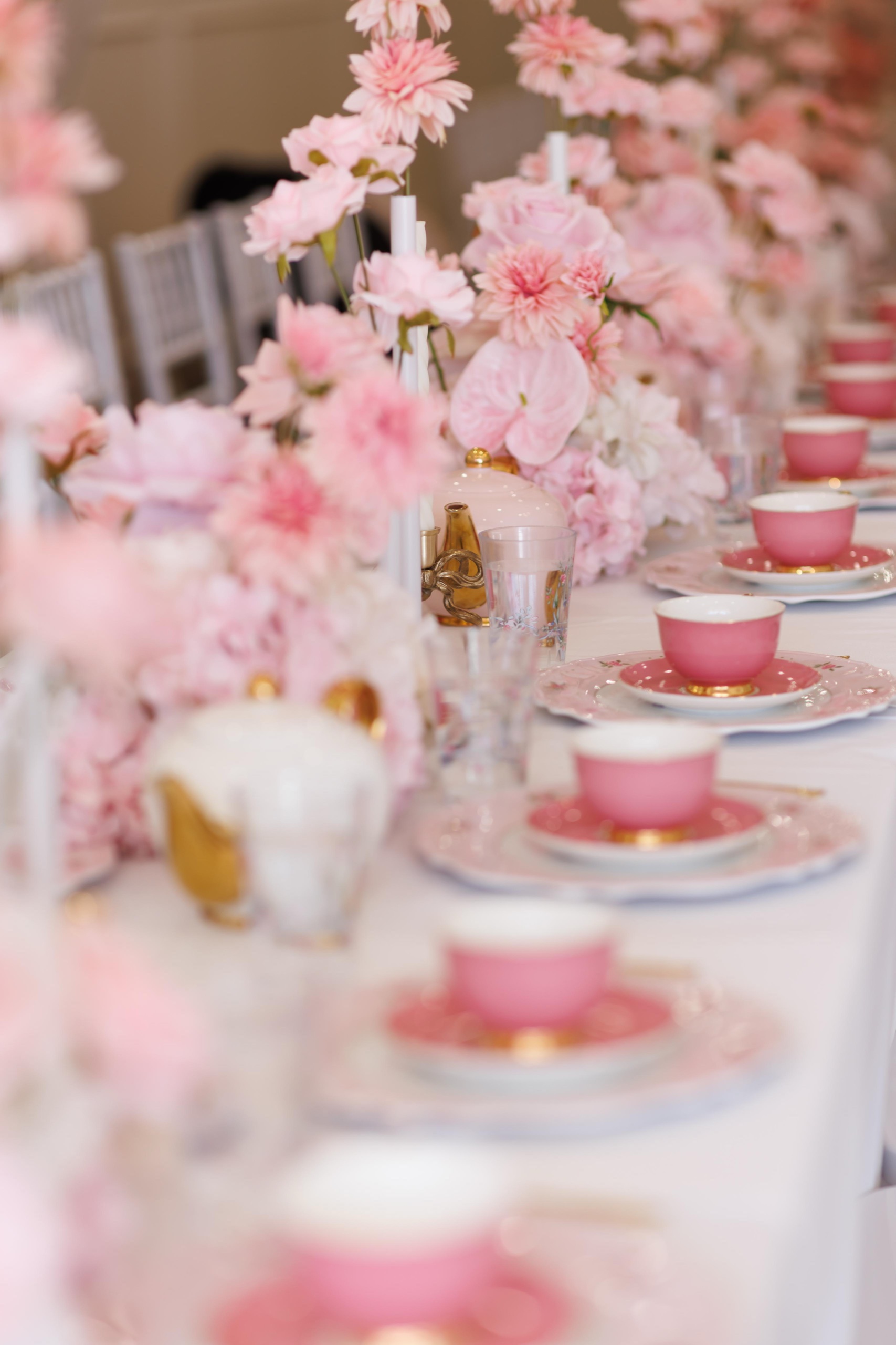 A long table laid with pink china and flowers for a high tea