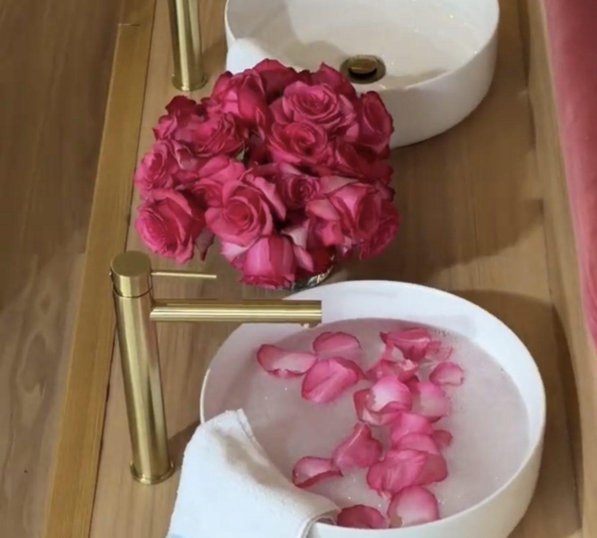 Pedicure bowls with gold taps, pink roses and rose petals floating in the water