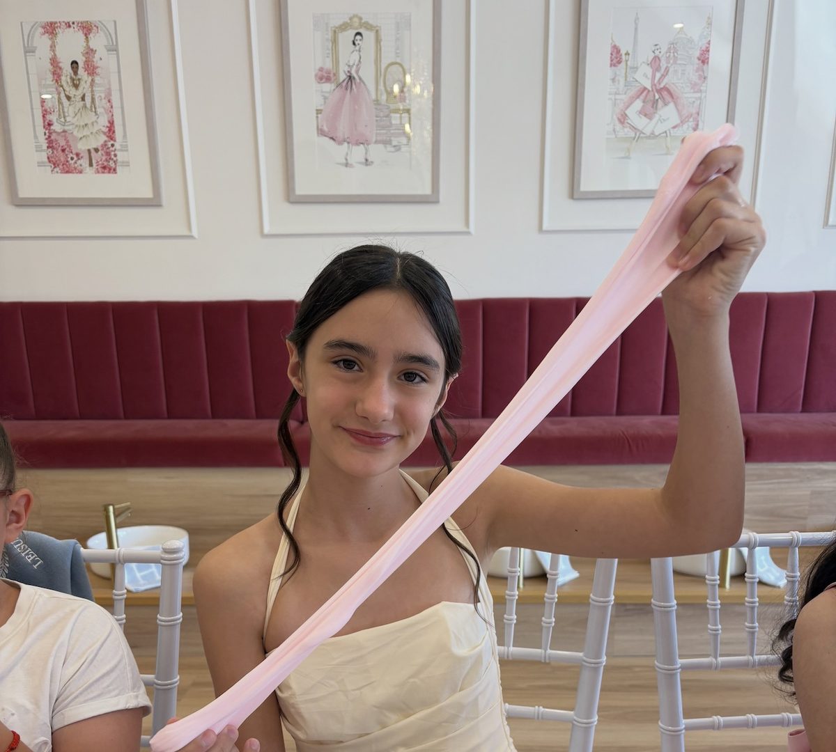 A girl stretching pink slime at a slime party